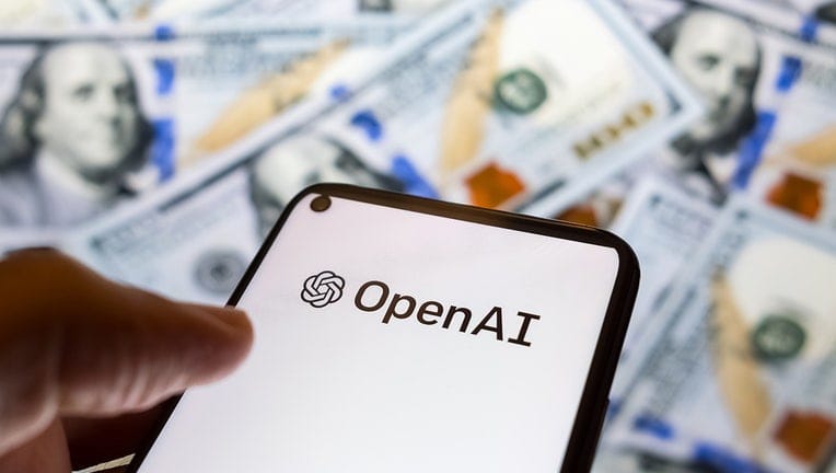 Логотип OpenAI на смартфоне на фоне долларовых купюр