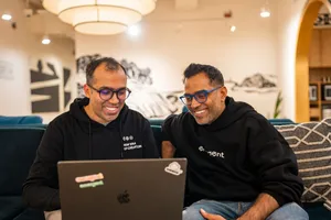 Сооснователи Emergent Madhav Jha и Mukund Jha за ноутбуком после раунда AI coding стартапа
